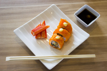Sushi rolland crab with chopstickson on white plate and soy sauce
