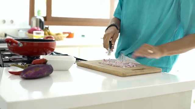 Woman puts chopped onion on the frying pan, steadycam shot
