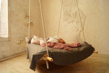 Hanging bed in rural or loft bedroom interior.