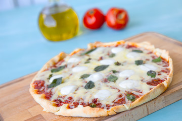 pizza with olive oil and tomatoes on a blue background