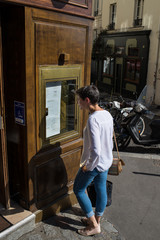 Fototapeta na wymiar Jeune femme lisant le menu à l'entrée d'un restaurant à Paris