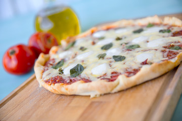 pizza with olive oil and tomatoes on a blue background