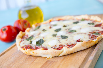 pizza with olive oil and tomatoes on a blue background