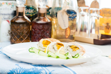 traditional Polish dishes. Front view of appetizing delicious meat snacks with lemon and cucumber on a white plate. On the background different in the shape bottles with the oil