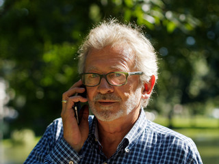 Aktiver Rentner im Park telefoniert mit Smartphone