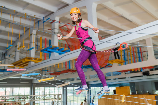 Young woman walking on a ladder in rope park gym indoors