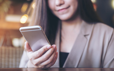 A beautiful Asian business woman with smiley face using and looking at smart phone in modern cafe