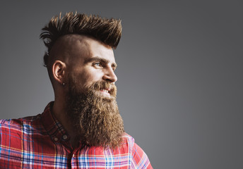Young trendy man portrait. Punk styled man with Mohawk hairstyle is smiling. Isolated on gray...