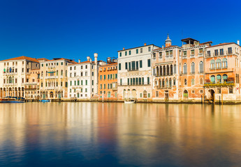 Fototapeta na wymiar Venice, Italy: Old houses in the traditional Venetian architecture style reflected in the Grand Canal of Venice. Long exposure photo