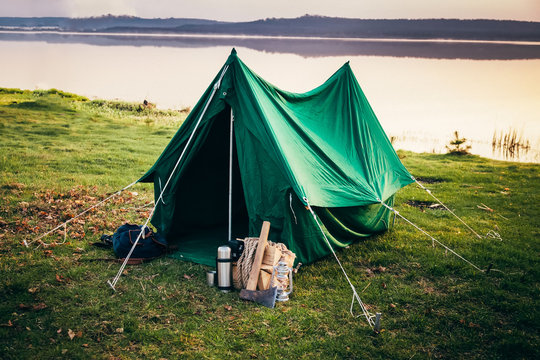 Green tent standing on the coast of the lake in the misty mornin