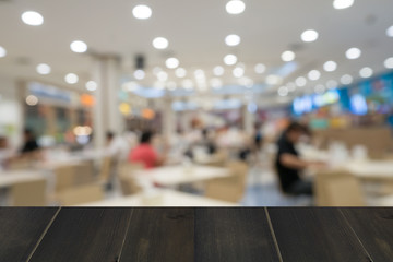 wooden table with abstract blur of food court background