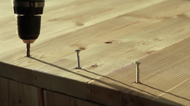 Screwing a screw into wood with a screwdriver. Closeup screwdriver