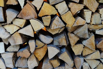 Stacks of chopped wood logs against a wall outdoors