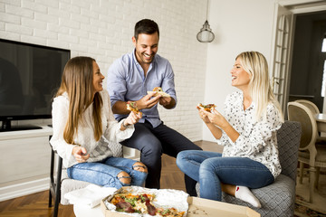 Young friends eating pizza in the room