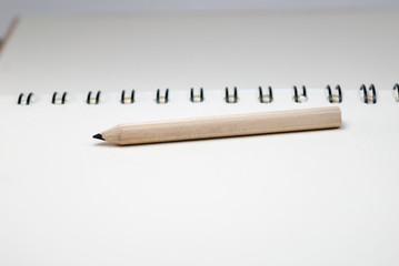 Notebook paper on white background and black pencil