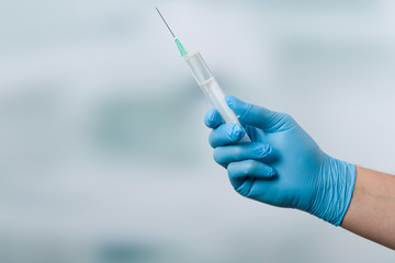 Hand mit Medizinhandschuh hält eine aufgezogene Spritze