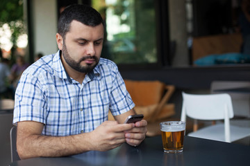 Fototapeta na wymiar Handsome man using phone in bar