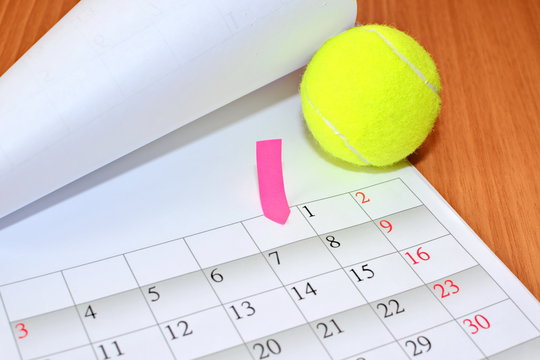 bent clean sheet monthly calendar June new year 2018 with paper label, tennis ball on wooden table close up