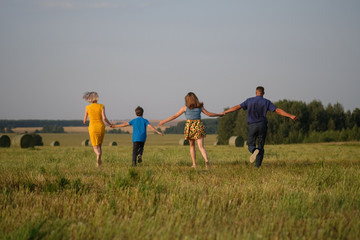 mom, dad, son and daughter running across the field