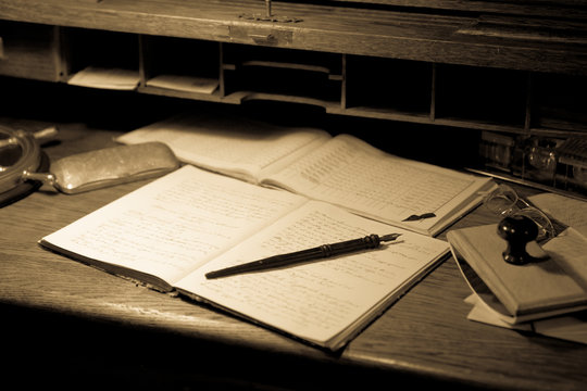 Vecchi documenti con penna in uno scrittoio di legno - stile seppia