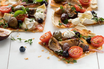 Delicious a slice of flatbread pizza on a white wooden table. Top view.
