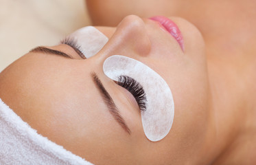 Beautiful Woman with long eyelashes in a beauty salon. Eyelash extension procedure. Lashes close up