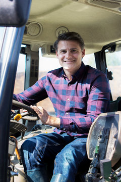Portrait Of Farmer Sitting In Cab Of Tractor