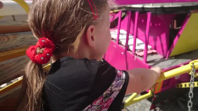 Cute small girl on funfair attraction. Funfair carousel. Cheerful happy girl screaming during carousel ride.