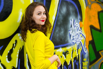 Portrait of cute girl in yellow pullover on graffiti wall background