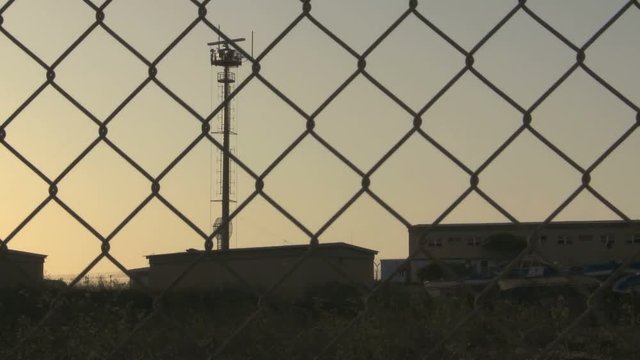 Radar tower communication behind fence at sunset