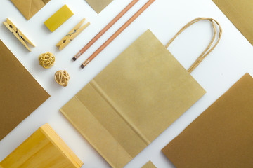 Top view of white table with pencil, notebook, brown paper and paper bag