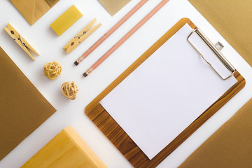 Top view of white table with pencil, notebook, brown paper ,paper bag and clipboard