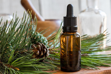 A bottle of pine essential oil with pine twigs