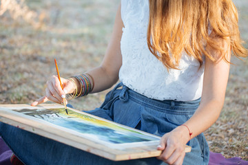 Charming woman finishing draw a beautiful landscape at the park