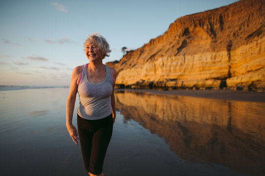 Active senior woman on beach at sunset