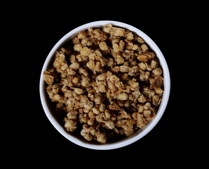  Crunchy granola, muesli pile with nuts in bowl isolated on black background,