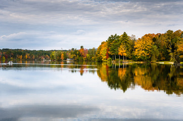 Autumn Trees on the Shore of a Lake reflecting in the Calm Waters on a overcast Autumn Day. The Berkshires, MA, USA