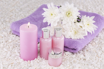 Obraz na płótnie Canvas Spa. Still life. Candle of pink color, a towel and white flowers on a background of white pebbles