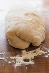 Loaf of homeade French baguette dough resting on wooden surface