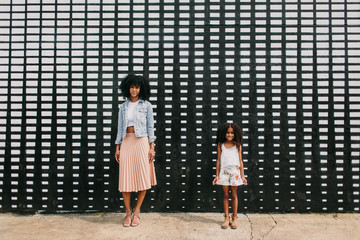 Portrait of a mother and daughter posed on a sidewalk in the city