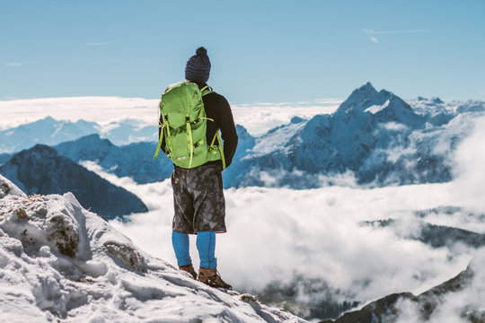 male mountaineer with boardshorts overlooking the snowcovered mo