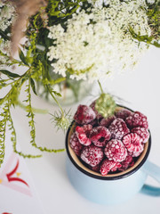 Wildflowers and frozen raspberries on a white table
