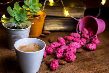 Cup of espresso coffee with french pink candies St. Genix the greasy plants and old books on the background.