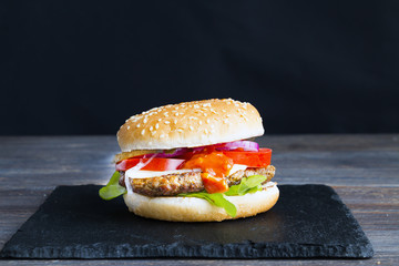 Burger on balck slate plate. Black background. Copy space. Closeup.