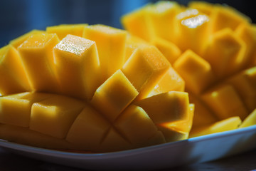 Natural Fresh Ripe Mango ubes, Slices close up, Macro shooting. On the dark blue or black background. On the rustic wooden board and bamboo napkin 07
