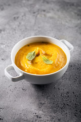 Creamy pumpkin soup puree in tbowl on table ready to eat