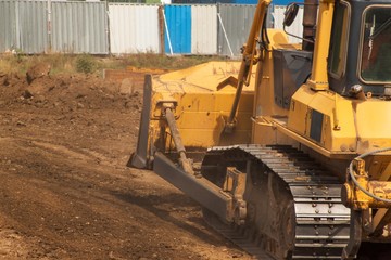 Fototapeta premium Excavator working on a construction site. Yellow Construction bulldozer at Work. Construction of a new road.
