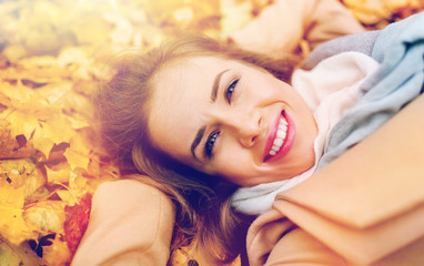 beautiful happy woman lying on autumn leaves