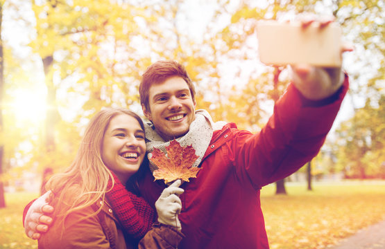 couple taking selfie by smartphone in autumn park