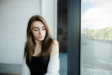 Portrait of trendy young caucasian woman posing near a window.